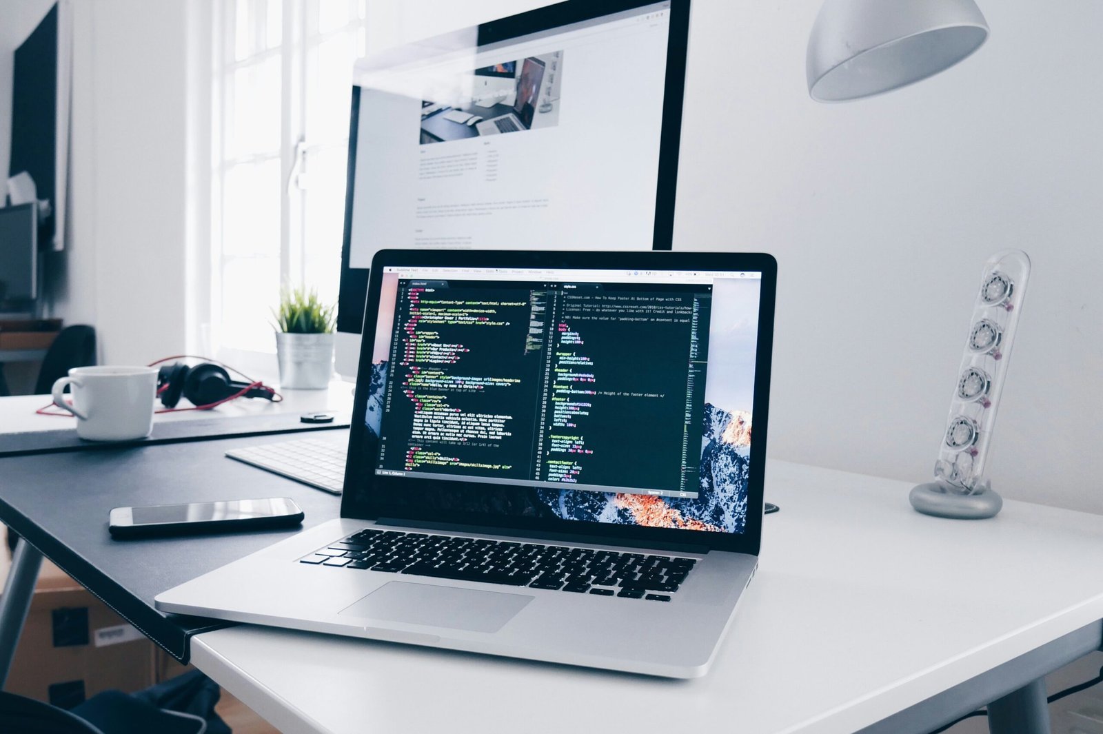 A-MacBook-with-lines-of-code-on-its-screen-on-a-busy-desk-scaled-1 Ordenador portátil barato: bueno, bonito y barato